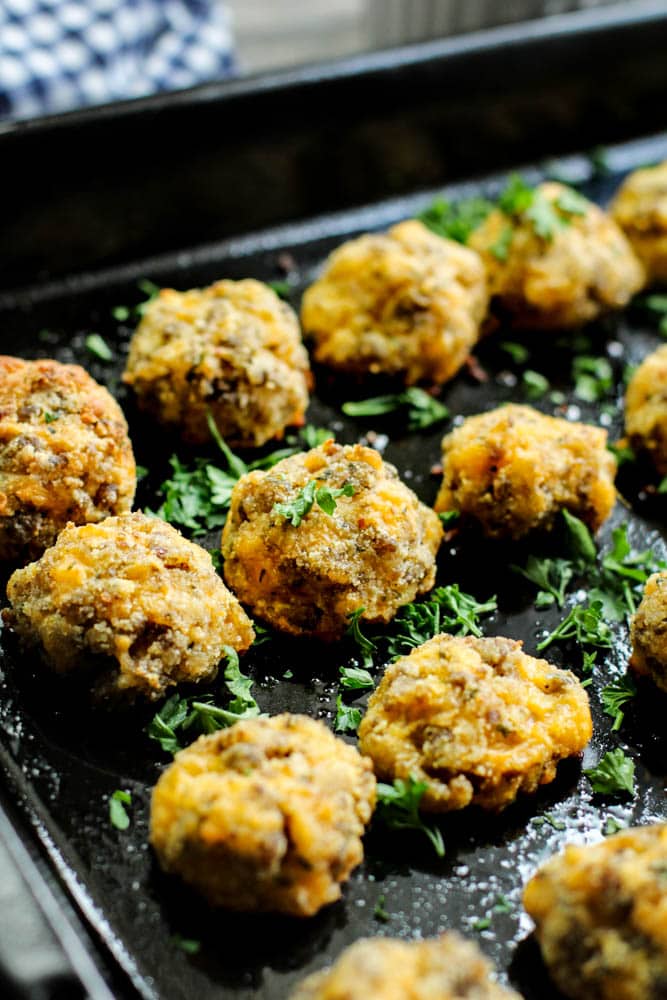 low carb sausage keto balls on a black baking tray with parsley garnished over it