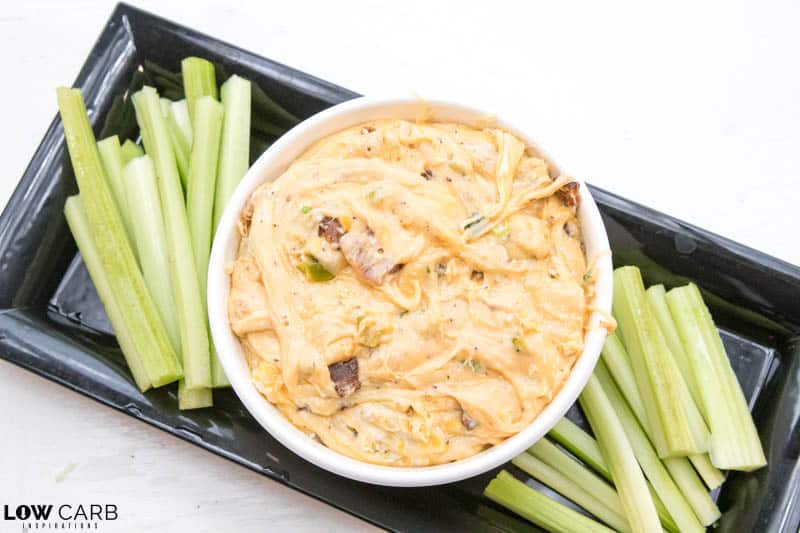 jalapeno popper dip in a white bowl with celery on a plate
