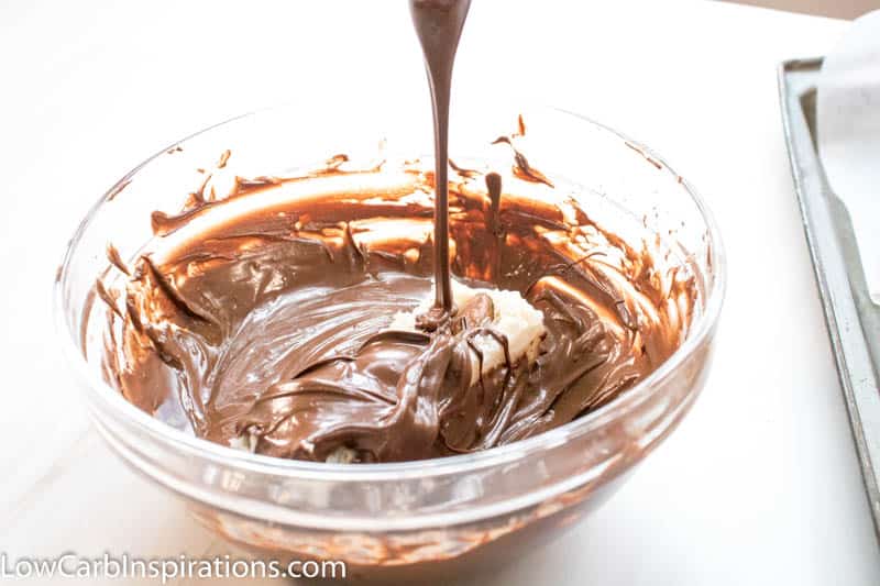 Bowl of melted chocolate with frozen fat bomb being dipped