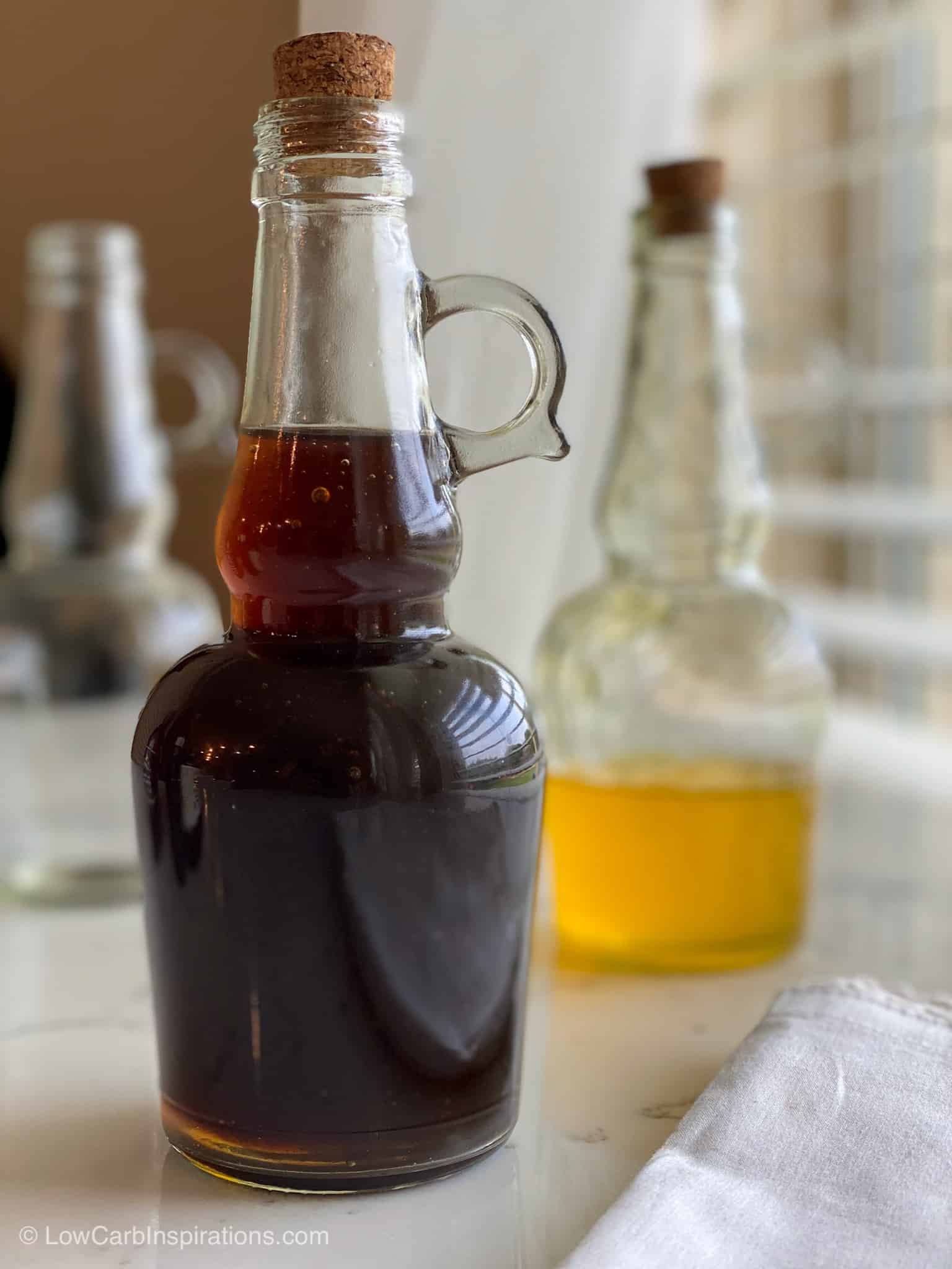 Clear bottle of sugar free keto maple syrup with a banana syrup in the background