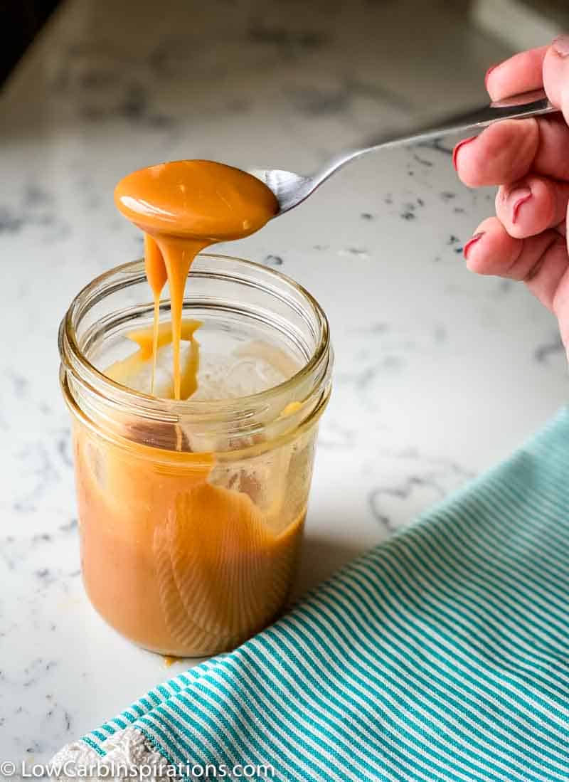 sugar free caramel sauce in a mason jar with a spoon showing the texture of the caramel