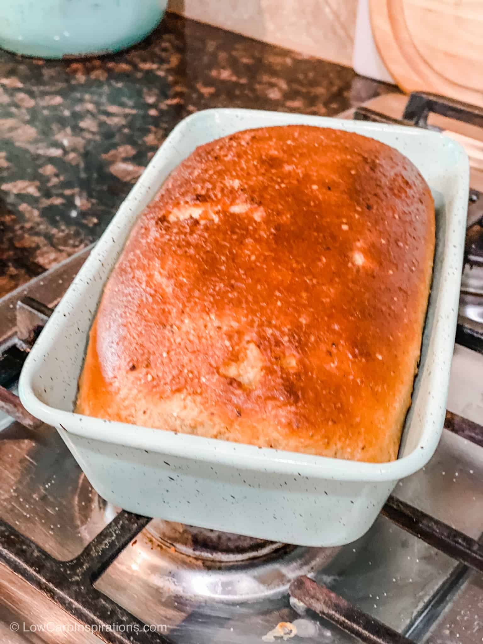 Keto Rye bread cooked in a blue bread pan sitting on top fo the stove