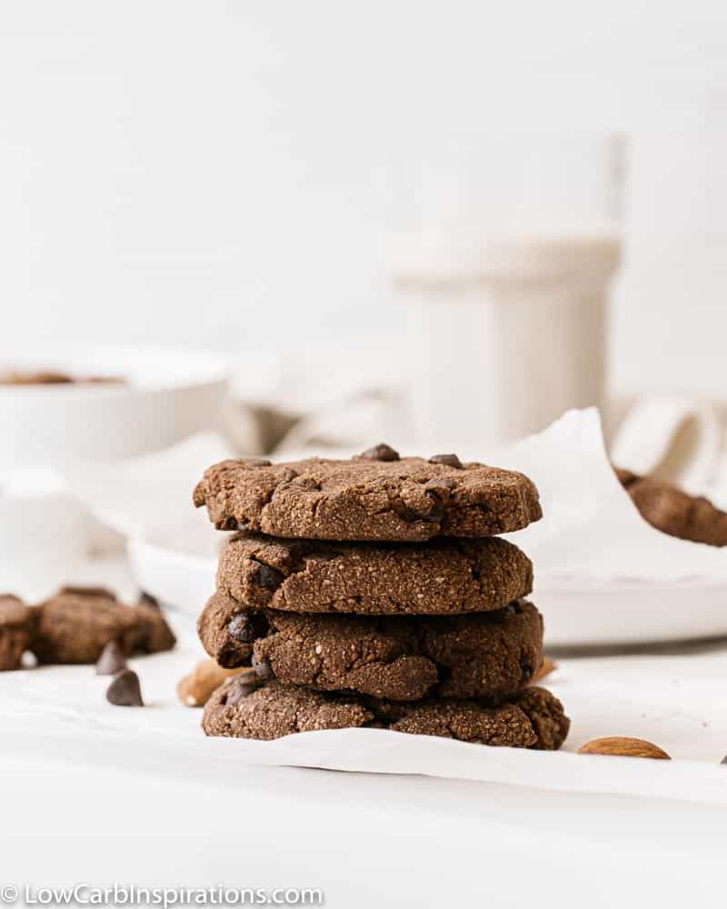 stacked sugar free chocolate cookies with a glass of milk in the background