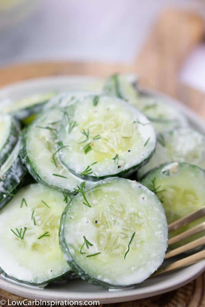 Close up of dill cucumber salad recipe on a white plate with a fork