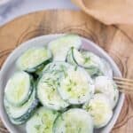 overhead photo of quick and easy cucumber salad on a white plate and cutting board