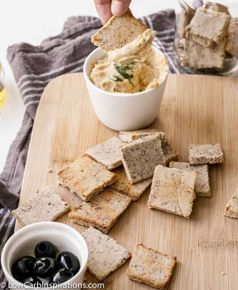 Homemade Almond Flour Crackers on a wood cutting board with dip in a bowl