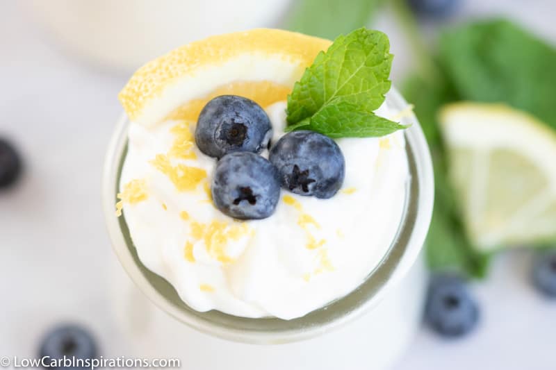 Close up of Low Carb Lemon Mousse with lemon and blueberries in a small clear glass