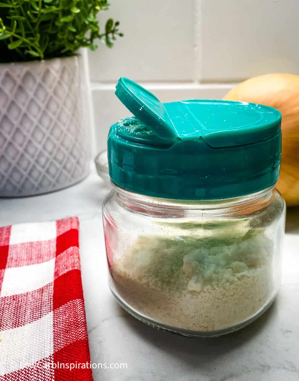 Small mason jar with a green shaker lid and the jar is filled with parmesan cheese