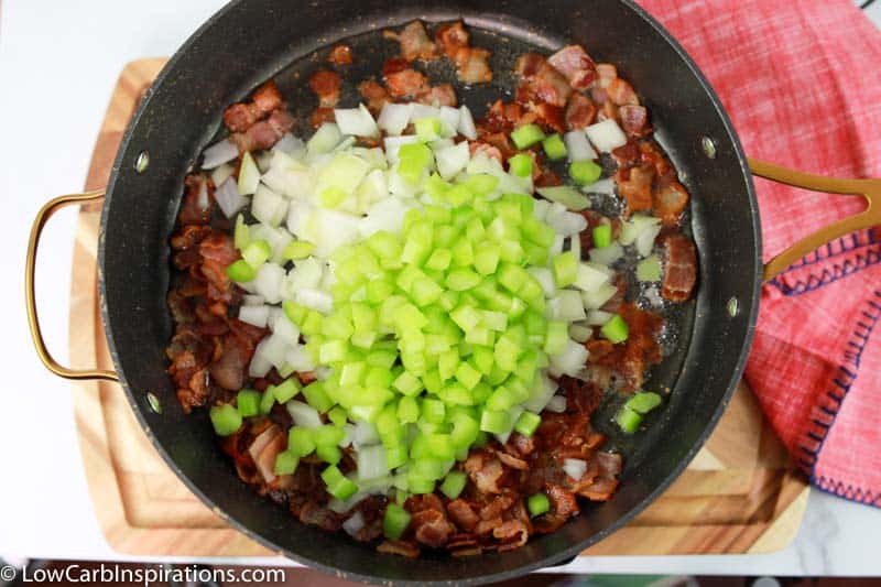cooked bacon, celery and onions in a black skillet