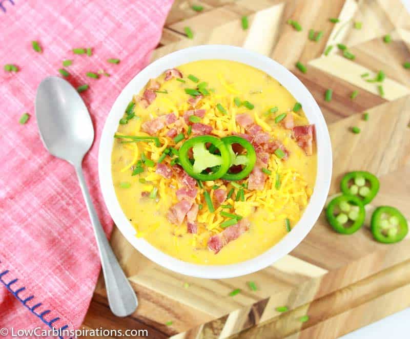 easy bacon cheddar keto soup recipe in a white bowl on a table with a spoon and jalapenos on the side