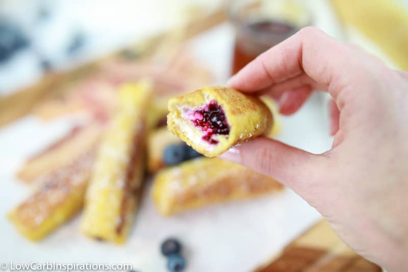 keto blueberry roll ups with a bite eaten in a hand