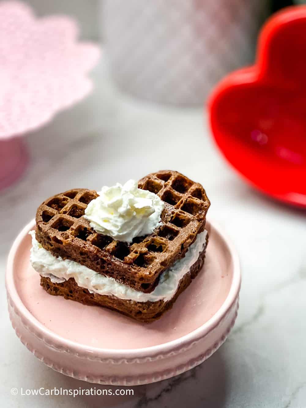 Heart shaped chocolate waffle cake on a pink cake plate stand