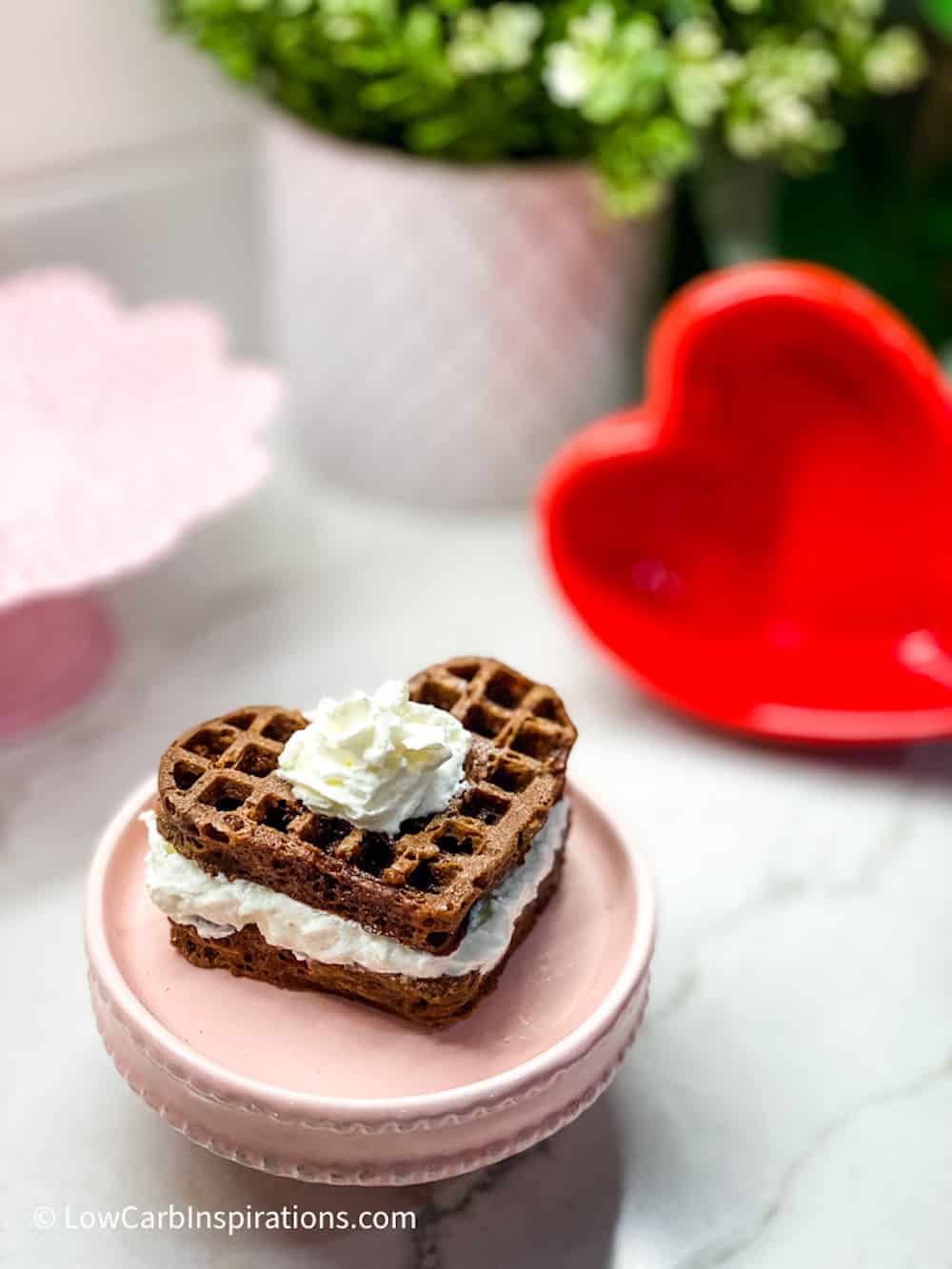 Chocolate Heart Shaped Waffle Cake on a pink cake plate topped with whipped cream 