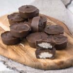 far away photo of chocolate coconut bonbons stacked on a wood cutting board