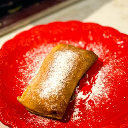 Pastry dessert dusted with sugar on a red plate