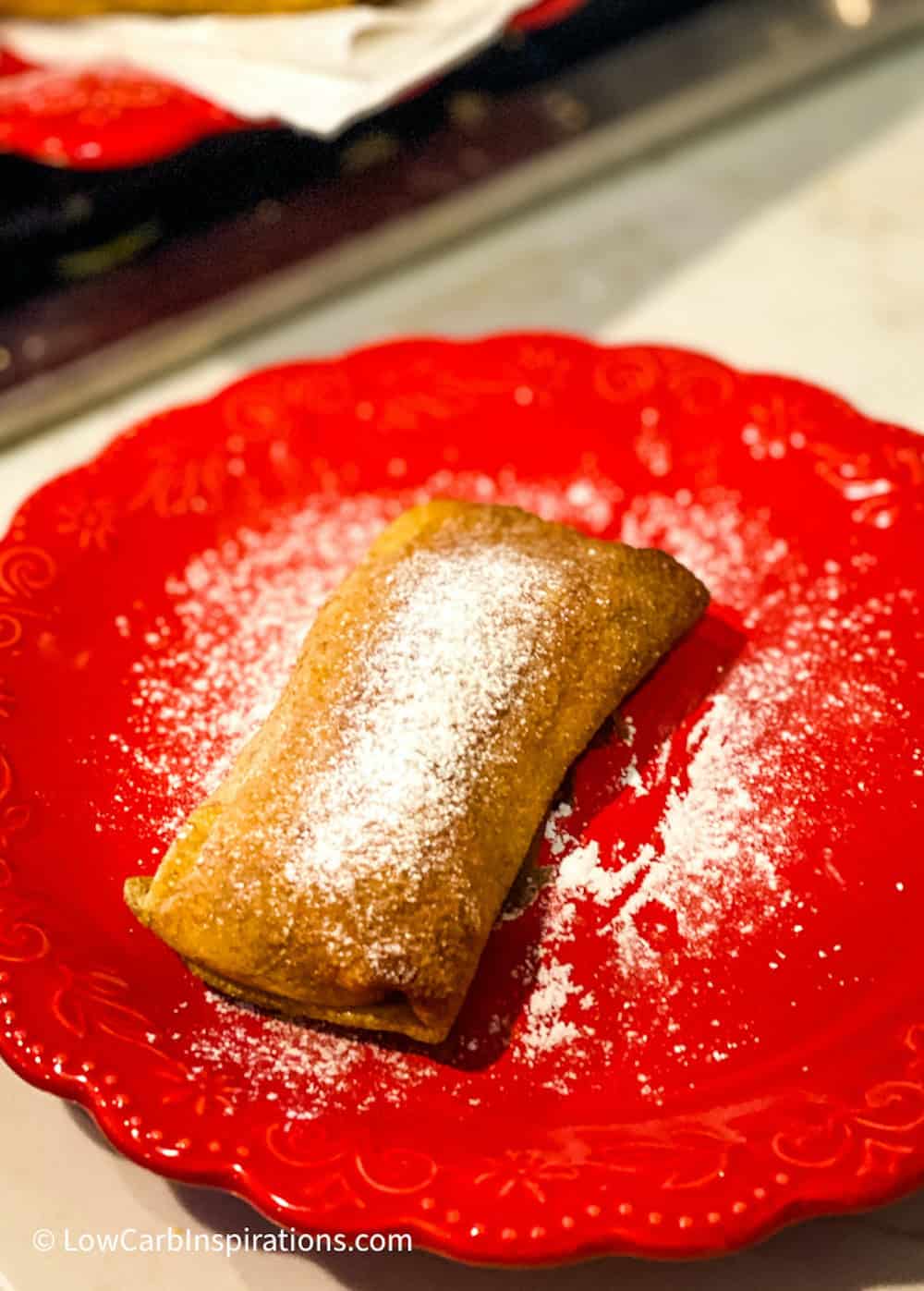 Pastry dessert dusted with sugar on a red plate