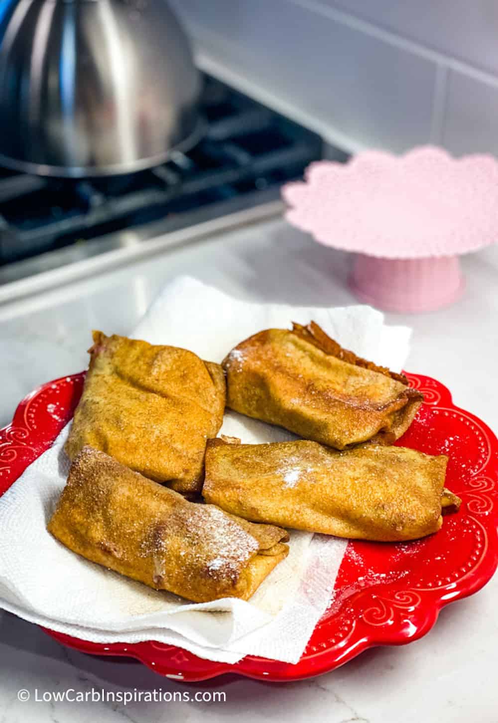 Finished strudels sitting on a paper towel on a red plate.