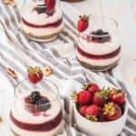 berry parfait recipe on a table with strawberries next to it and more parfaits in the background