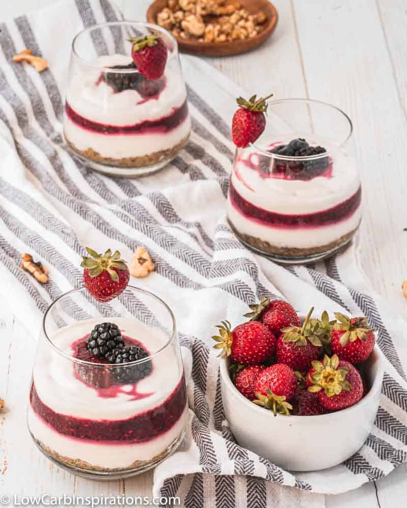 berry parfait recipe on a table with strawberries next to it and more parfaits in the background