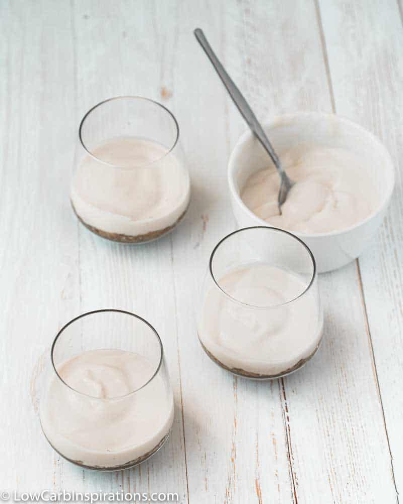 coconut yogurt in a clear glass with more next to it in a white bowl with a spoon inside
