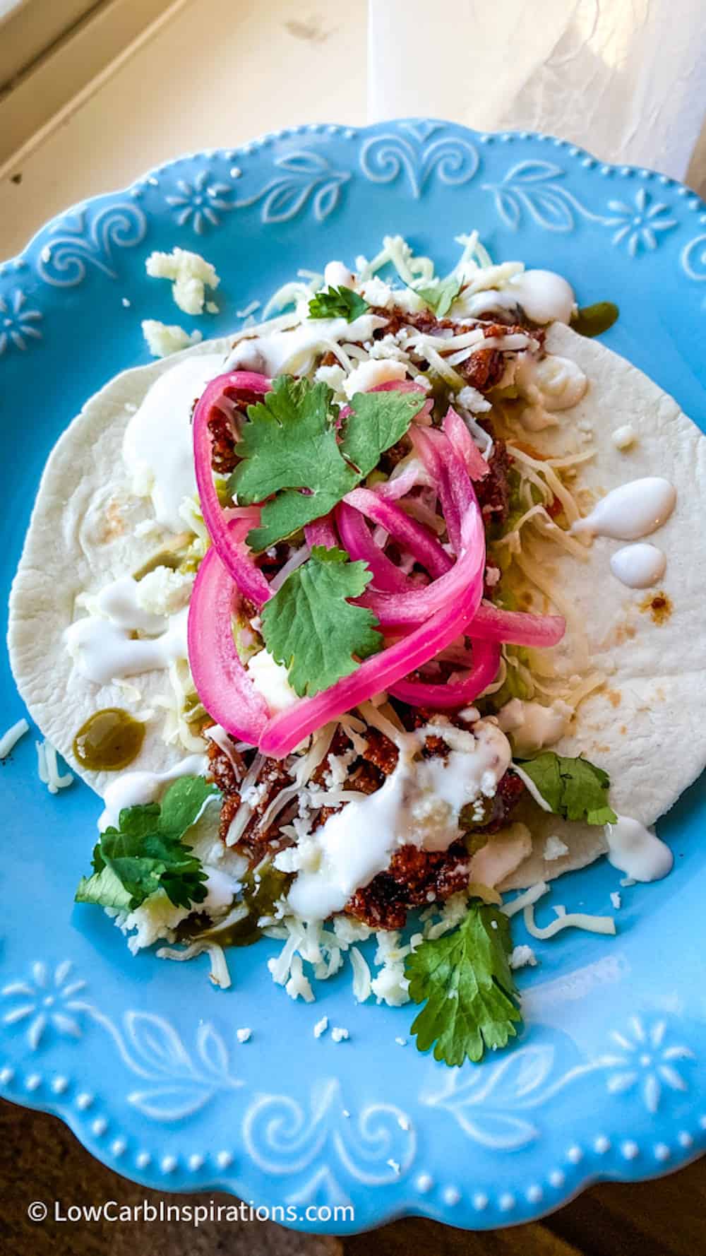 Taco with pickled red onions on a blue plate