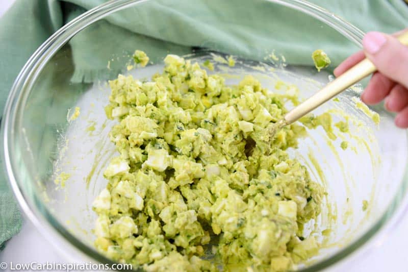 mixed avocado egg salad recipe in a clear bowl on a table with a fork in the bowl