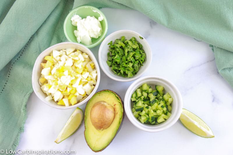 avocado egg salad recipe ingredients on a table with a towel in the background