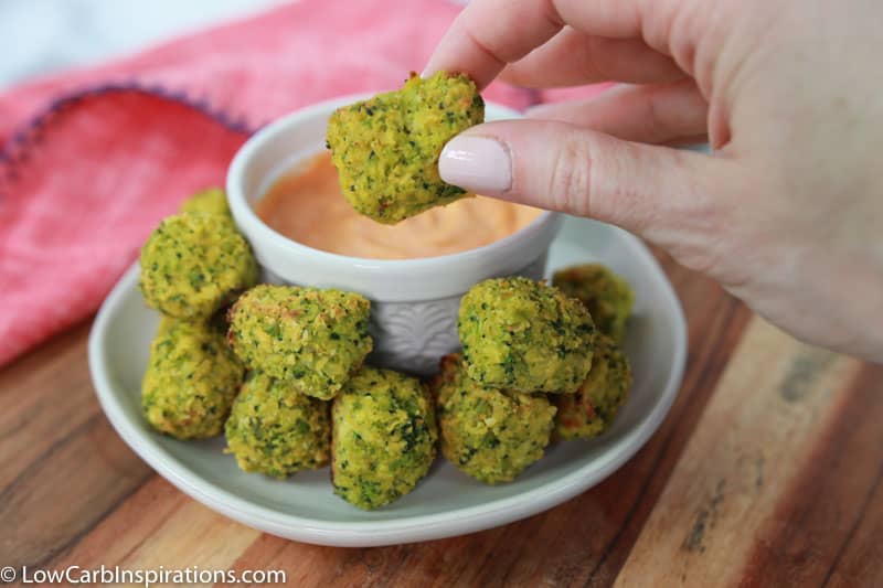 keto broccoli tots on a white plate with a white bowl of sriracha dipping sauce 