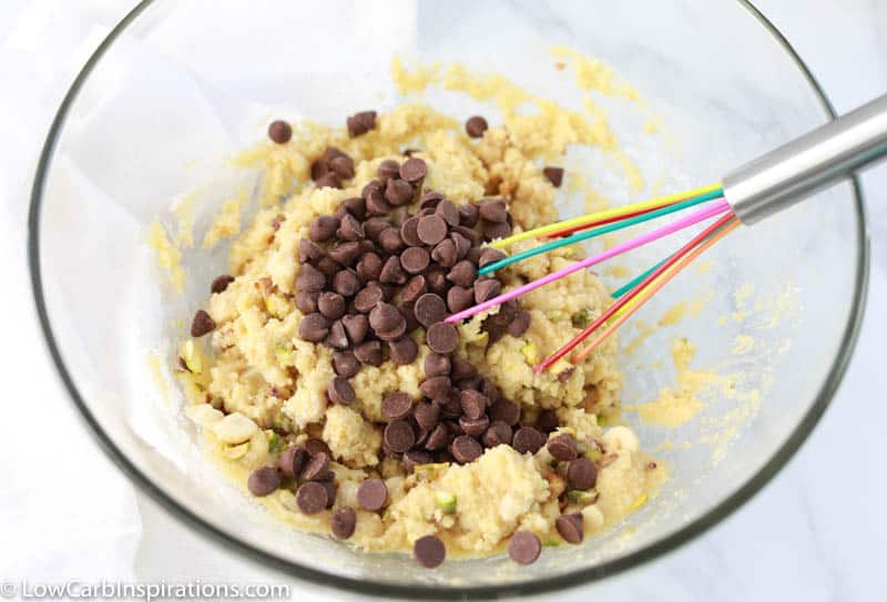 homemade kitchen sink cookie dough ingredients with chocolate chips in a clear bowl with a whisk