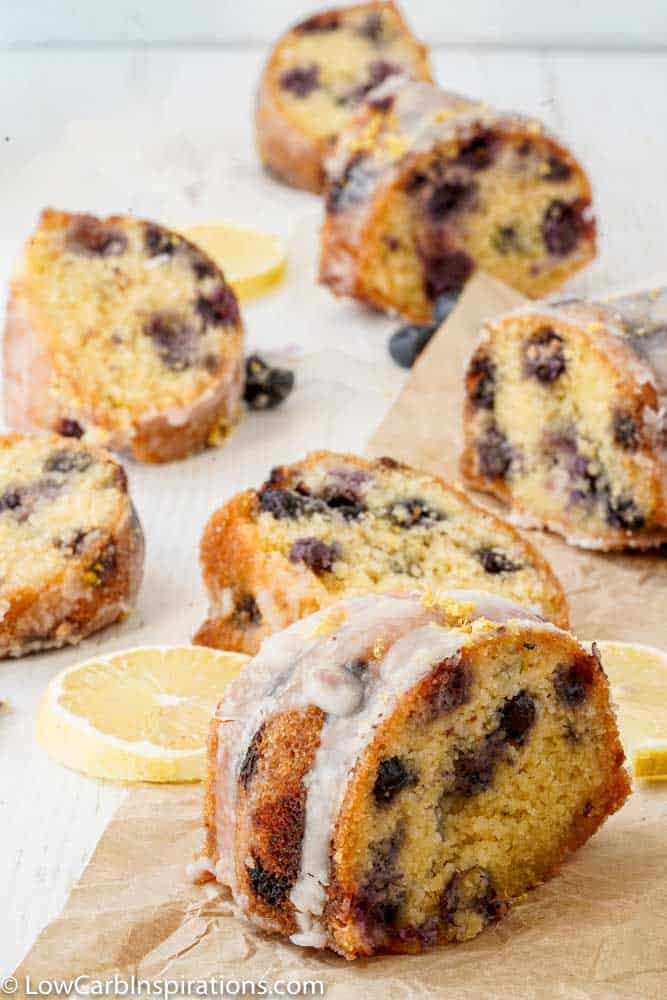 keto lemon blueberry cake sliced on brown parchment paper with lemon sliced on the table