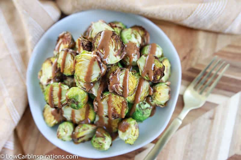 overhead photo of crispy brussel sprouts on a blue plate drizzled with mustard vinaigrette