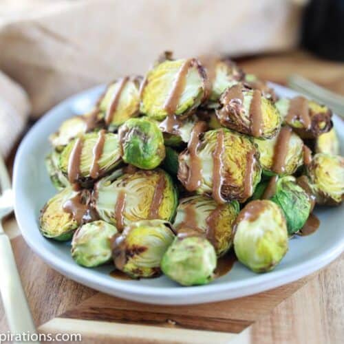 close up of keto brussel sprouts on a blue plate drizzled with mustard vinaigrette