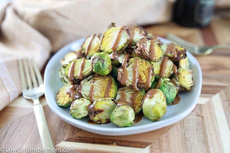 close up of keto brussel sprouts on a blue plate drizzled with mustard vinaigrette