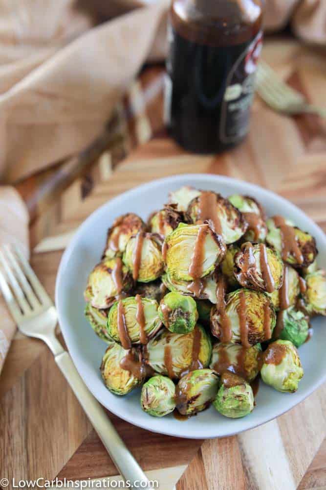overhead photo of crispy brussel sprouts on a blue plate drizzled with mustard vinaigrette