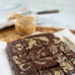 peanut butter swirl brownies on a wood cutting board cut into squares with more peanut butter in the background