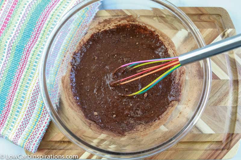 mixed homemade brownies in a clear bowl with a whisk inside