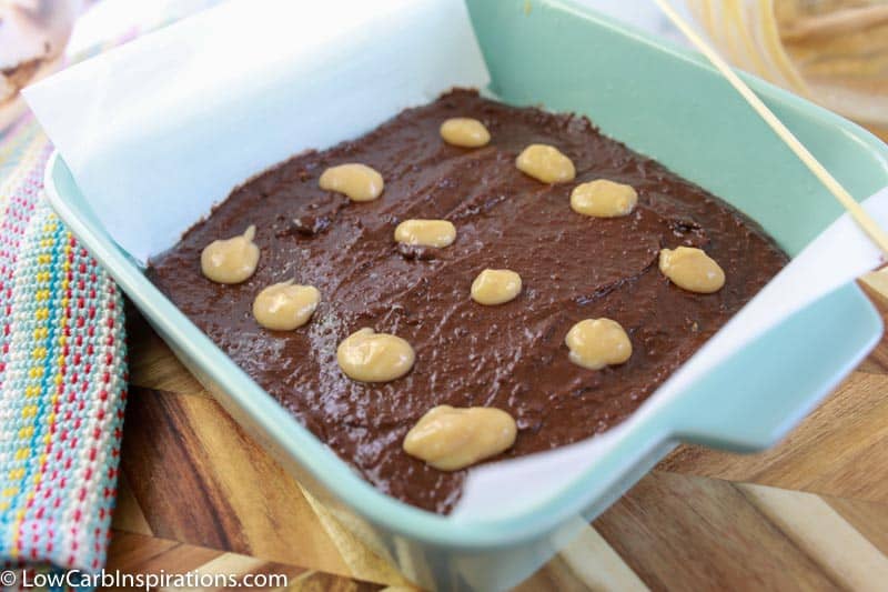 homemade keto brownie recipe in a baking dish with drops of peanut butter mixture on top