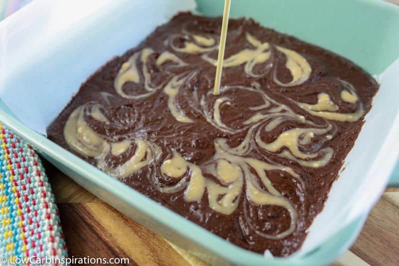 swirling peanut butter mixture into the homemade keto brownie mixture with a wooden skewer 