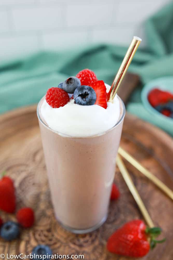 close up photo of the easy protein shake recipe in a clear class on a wood board with berries on the side