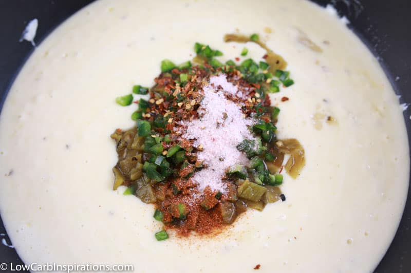 spices on top of melted cheese in a sauce pan