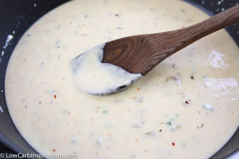 ingredients mixed into melted cheese in a sauce pan