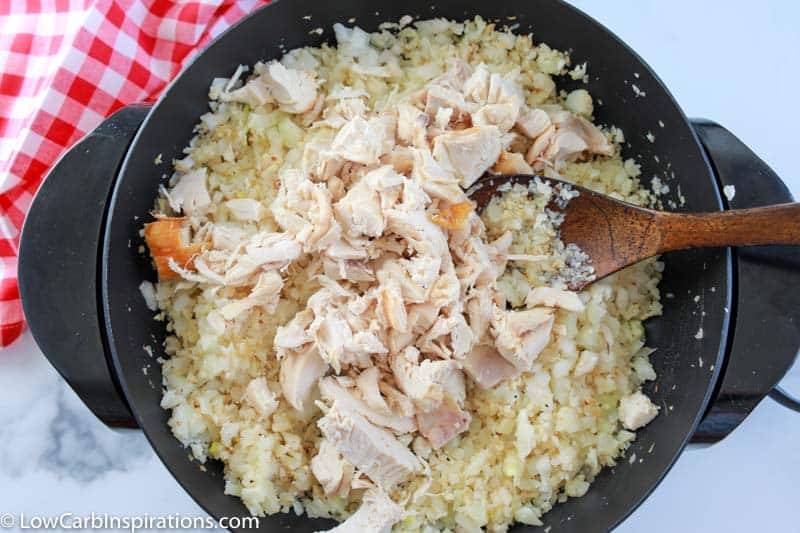 cauliflower rice and chicken in a wok cooking