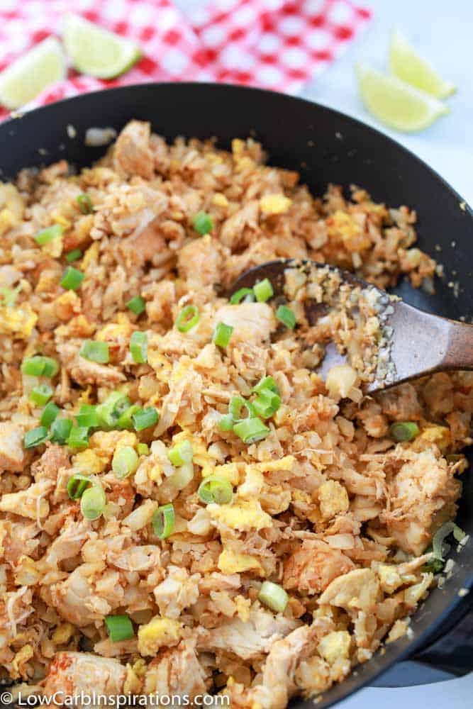 overhead photo of keto fried rice in a wok with a wooden spoon in the pan