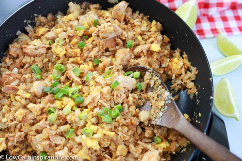 overhead photo of keto fried rice in a wok with a wooden spoon in the pan