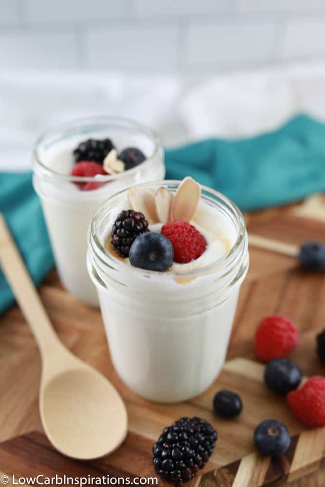 easy coconut yogurt ready to eat with a wood spoon and mixed berries on the side