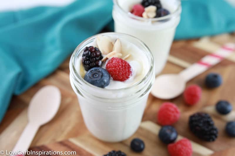 close up photo of easy yogurt recipe on a wood board with mixed berries and a wooden spoons on the side