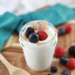 coconut yogurt recipe ready to eat with a wood spoon and mixed berries on the side