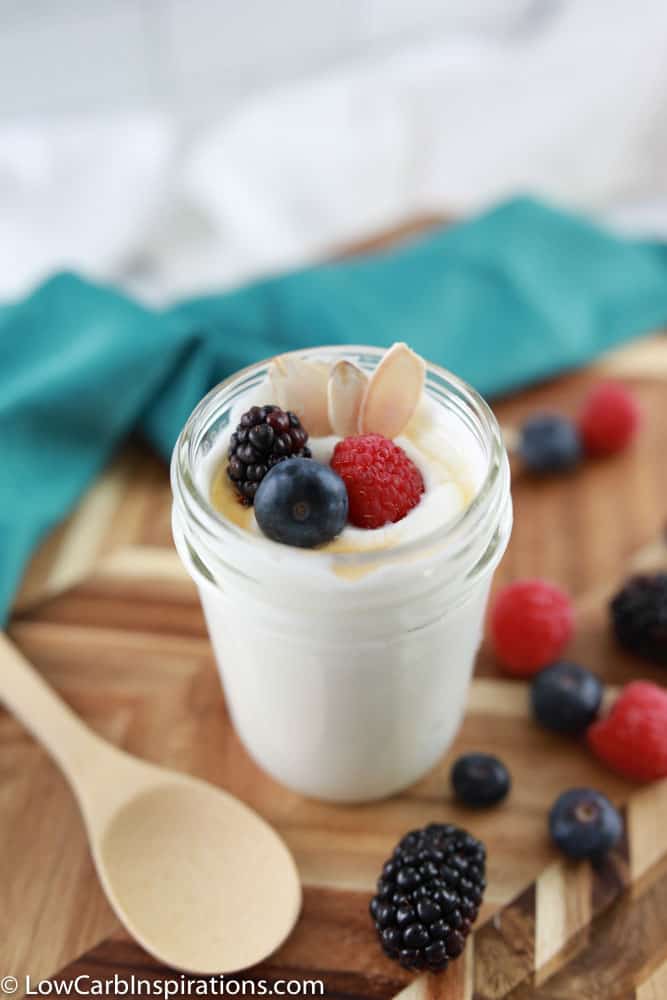 coconut yogurt recipe ready to eat with a wood spoon and mixed berries on the side