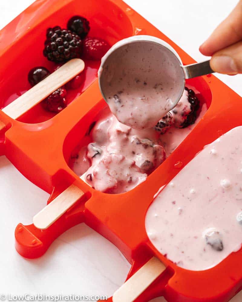 pouring triple berry popsicle ingredients into a popsicle mold