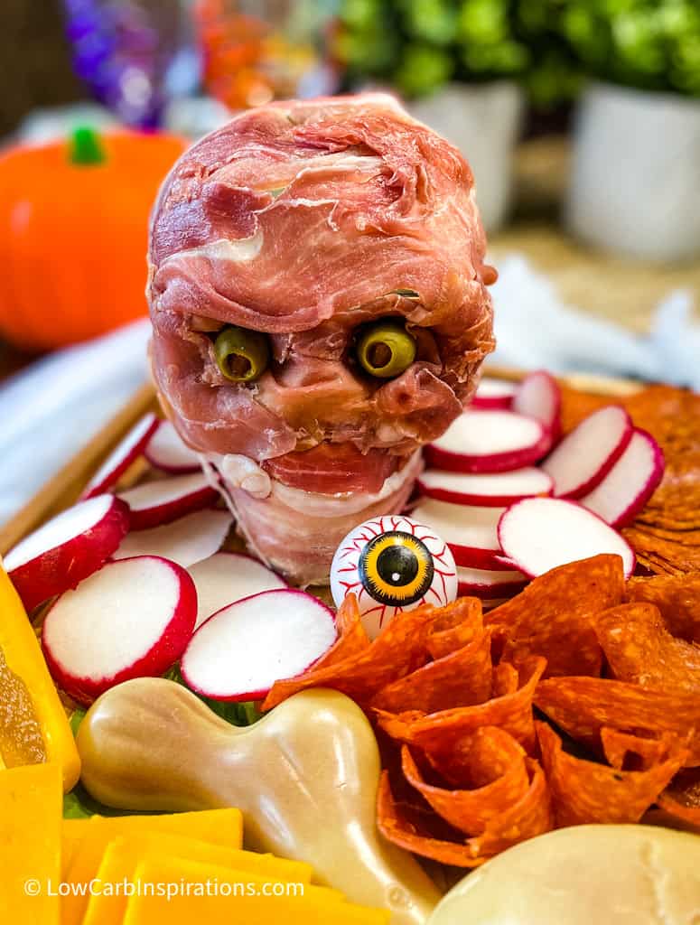 Skeleton head on a charcuterie board wrap in meat